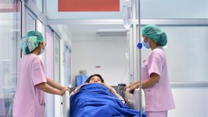 Woman doctors wheeling out a patient after surgery 