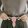Understanding Endometriosis Pain: Types, Triggers, and Coping Strategies 28 A woman holds up a paper cutout of a uterus, fallopian tubes, and ovaries