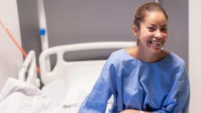 What to Expect Before, During, and After Laparoscopy Surgery for Endometriosis 13 Woman in a blue hospital gown smiling from a hospital bed